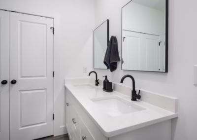 A clean white bathroom with black accents and a double vanity