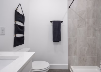 A clean white bathroom with black accents and a tiled standing shower.