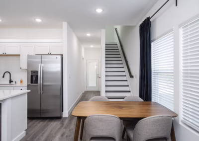 An open concept kitchen and dining room at the bottom of stairs leading to the second floor.