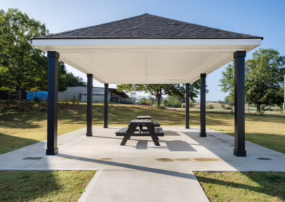 A picnic area on a cement patio under a large roofed pergola