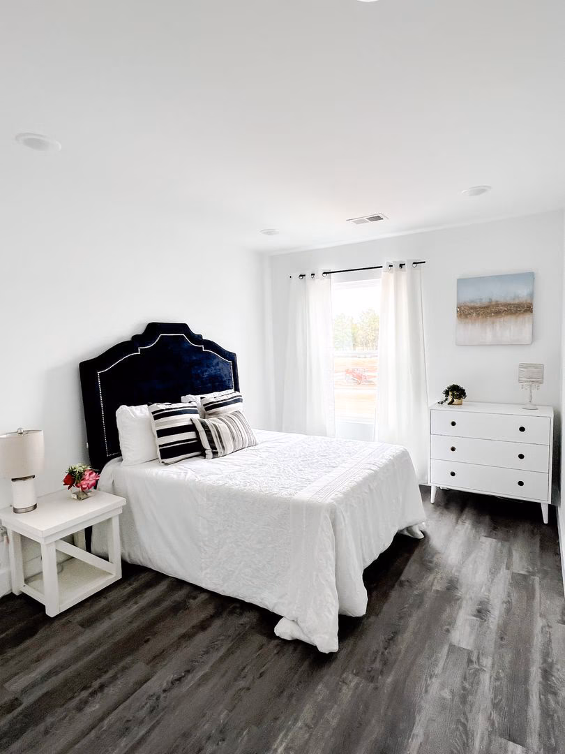 A clean white bedroom with hardwood floors