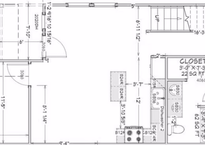 Blueprint layout for the downstairs area of a unit from Sage at Chelsey. Includes a one-car garage, open concept kitchen, dining, and living room, primary bedroom with ensuite bath and closet, stairs leading to second floor, and half-bath under the stairs.