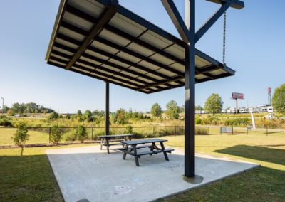 A shaded picnic area on a concrete patio surrounded by lush green lawn