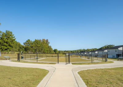 A cement walking path surrounding a fenced-in dog park area for use by Sage at Chelsey residents